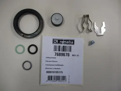 Remeha Teile mit einem Vibration Silencer, Gummiringen, Metallclips und Schraube, die auf einem hellen Hintergrund angeordnet sind.